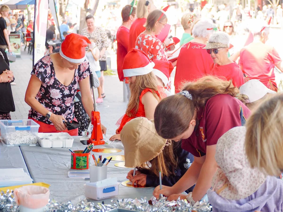 Children and parents doing Christmas crafts together at an outdoor market event